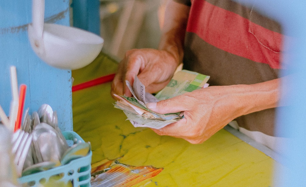 Hand counting money (credit: Irfan Hakin via Unsplash)
