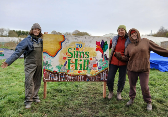 Sims Hill members standing next to the Sims Hill sign
